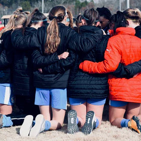 a female soccer team in a group huddle