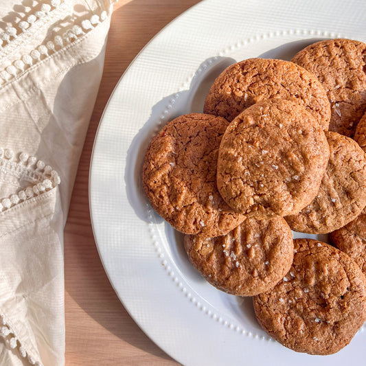 Cowgirl Peanut Butter Cookies on a white plate with a white cloth napkin next to it on a light wooden surface