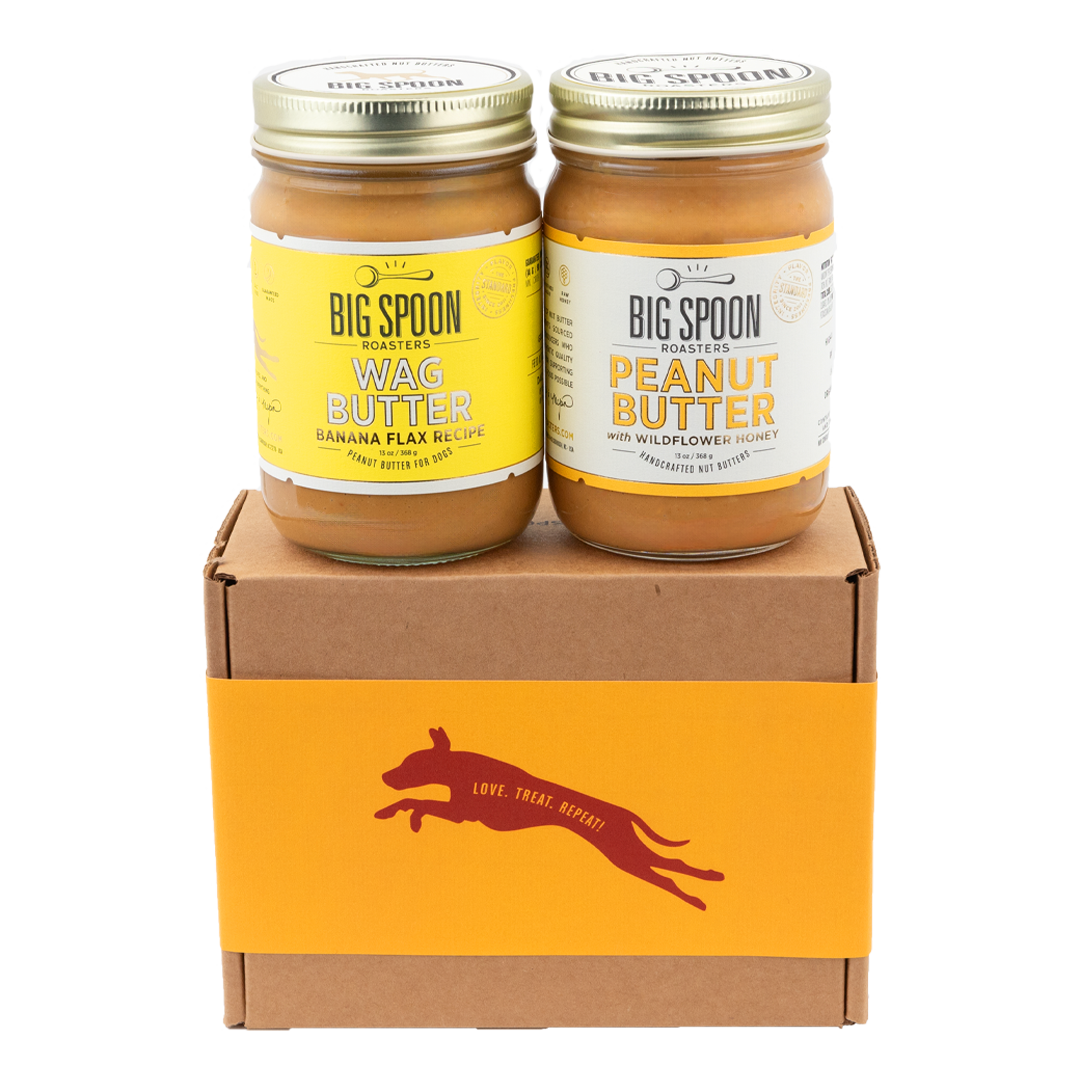 A jar of Banana Flax Wag Butter sits next to a jar of Peanut Butter on top of a gift box