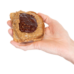 A hand holding a piece of toast with Almond Butter and jam