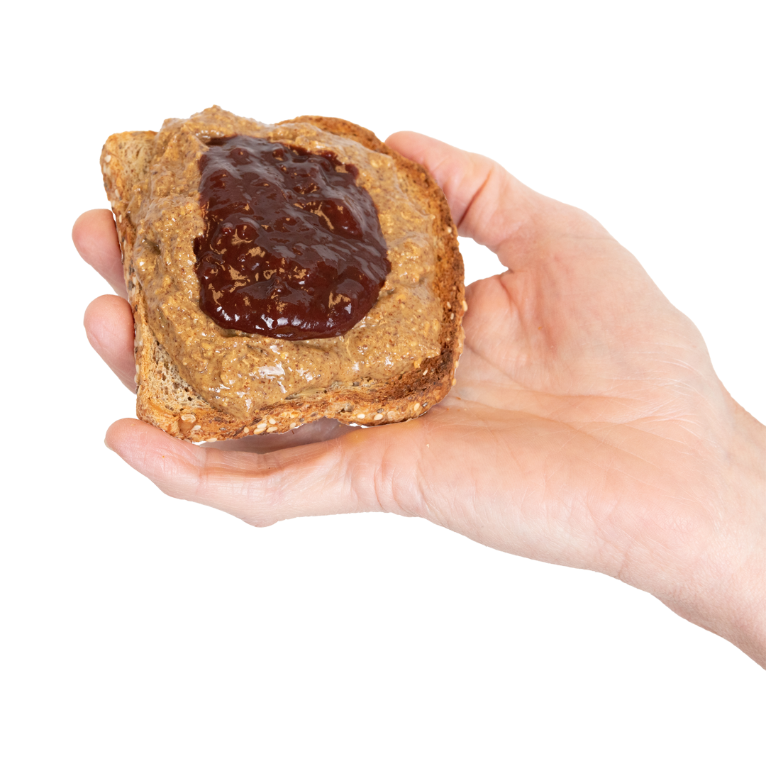 A hand holding a piece of toast with Almond Butter and jam