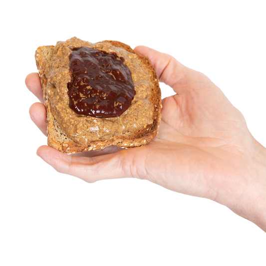 A hand holding a piece of toast with Almond Butter and jam