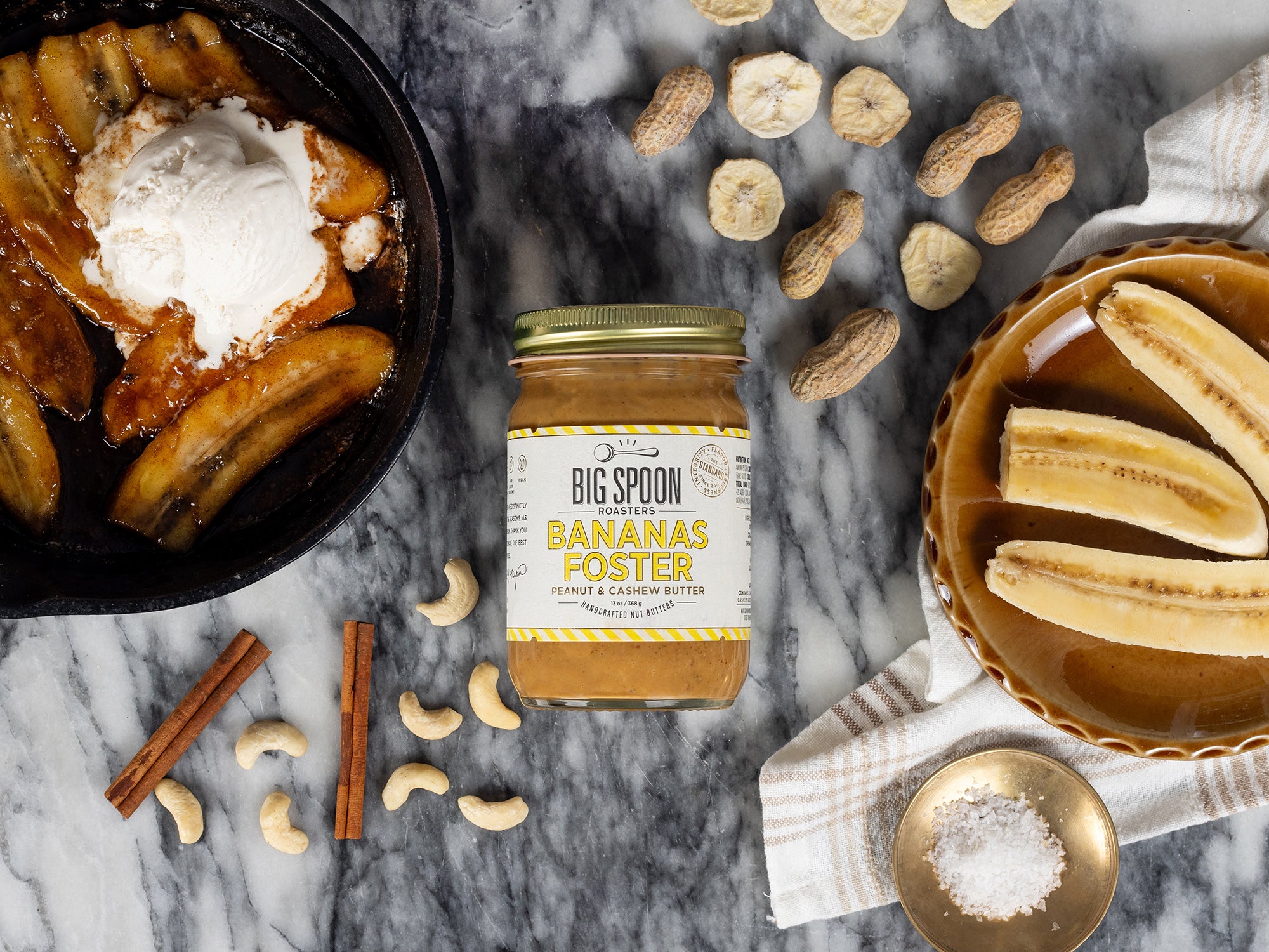 Jar of Bananas Foster Peanut & Cashew Butter styled with bananas and nuts