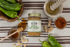 Jar of Hatch Hot Honey Peanut Butter surrounded by peanuts, hatch chiles, and honey