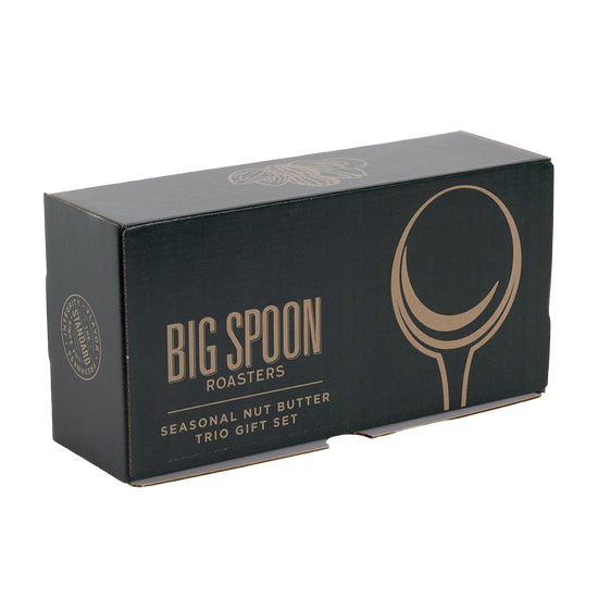 A dark green gift box for Big Spoon Roasters, featuring gold foil text that reads 'BIG SPOON ROASTERS' and 'SEASONAL NUT BUTTER TRIO GIFT SET', along with a large gold spoon graphic on the front, photographed on a white background.