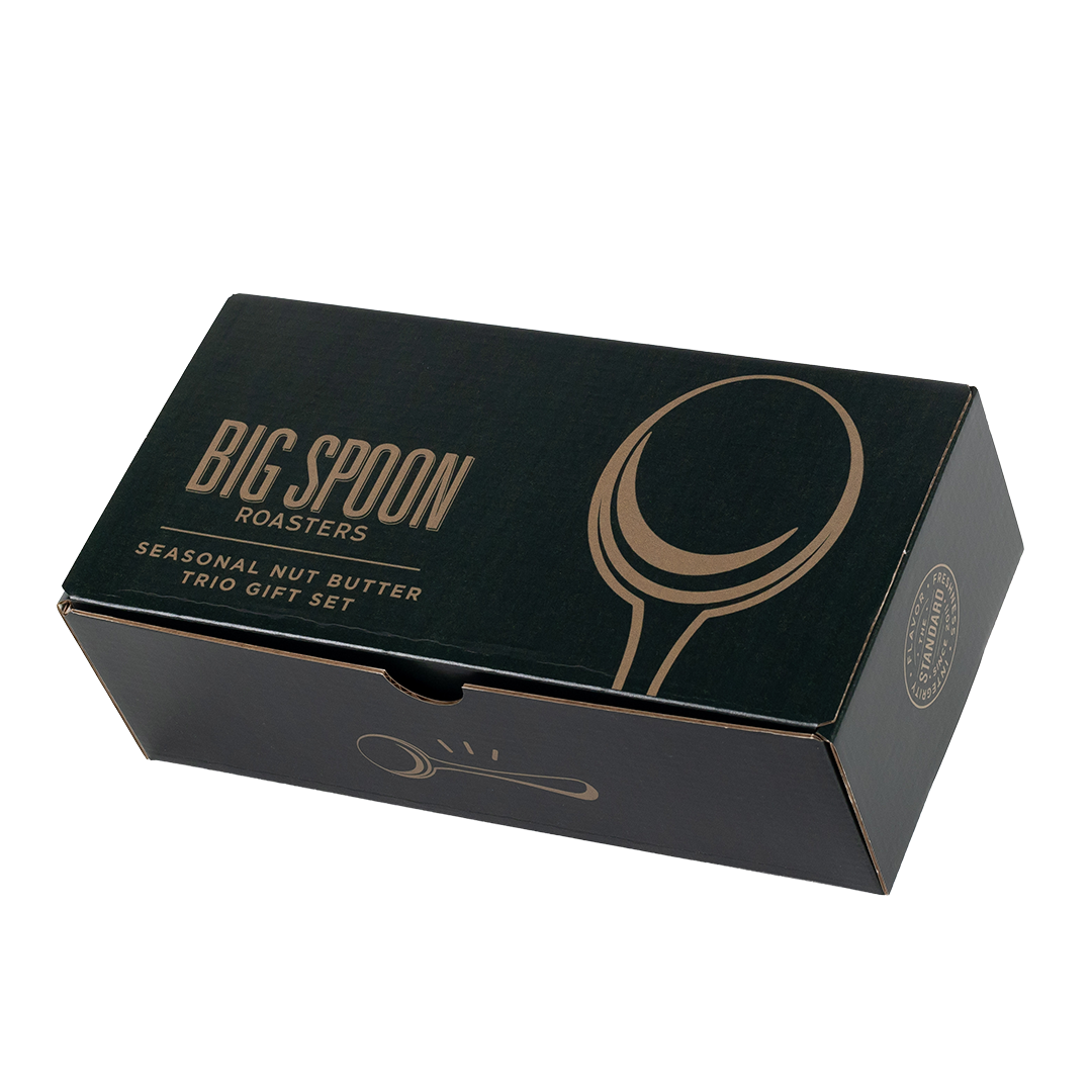 A dark green rectangular gift box for Big Spoon Roasters Seasonal Nut Butter Trio Gift Set, featuring gold foil text and spoon illustrations, photographed on a clean white background.