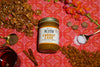 a jar Carrot Cake Almond & Walnut Butter surrounded by walnuts, a spoonful of spices, a jar of maple syrup, cinnamon sticks, whole nutmeg, a spoonful of sea salt, and almonds