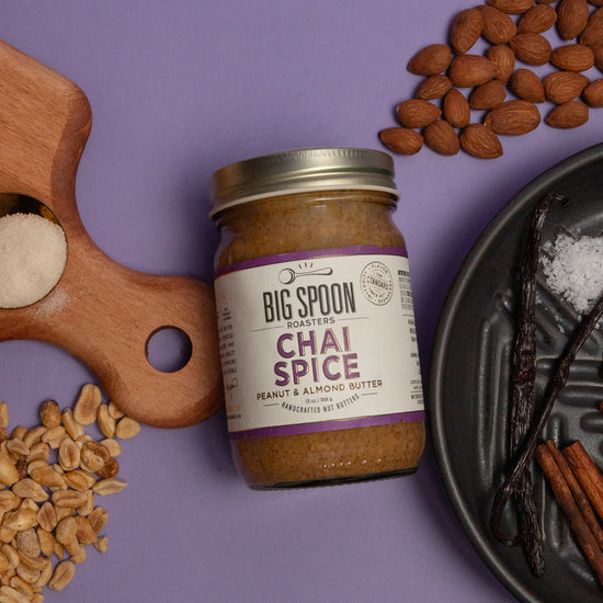 Jar of Big Spoon Roasters Chai Spice peanut and almond butter on a purple background with ingredients around it.