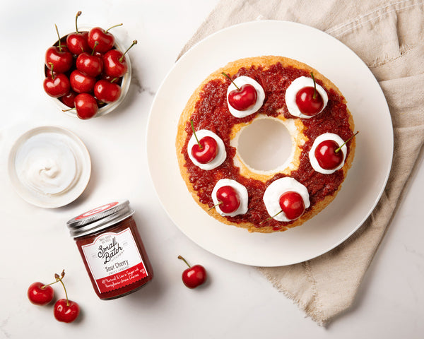 8 oz Small Batch Kitchen Sour Cherry Fruit Spread  with bowl of cherries and plate of cherry upside down cake on a white plate with a white background and linen napking