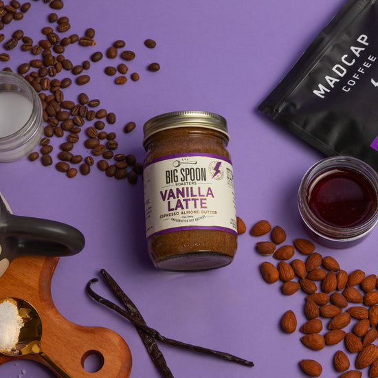 Vanilla latte jar, coffee beans, and coffee packaging on a purple background