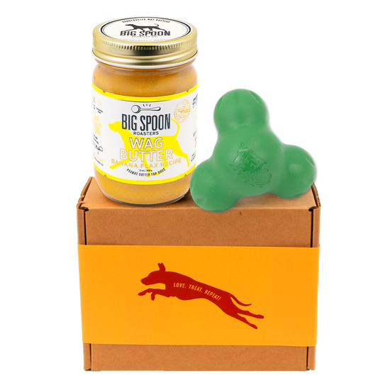 Jar of 'Big Spoon Roasters' Wag Butter on a box with a green West Paw Tux toy.