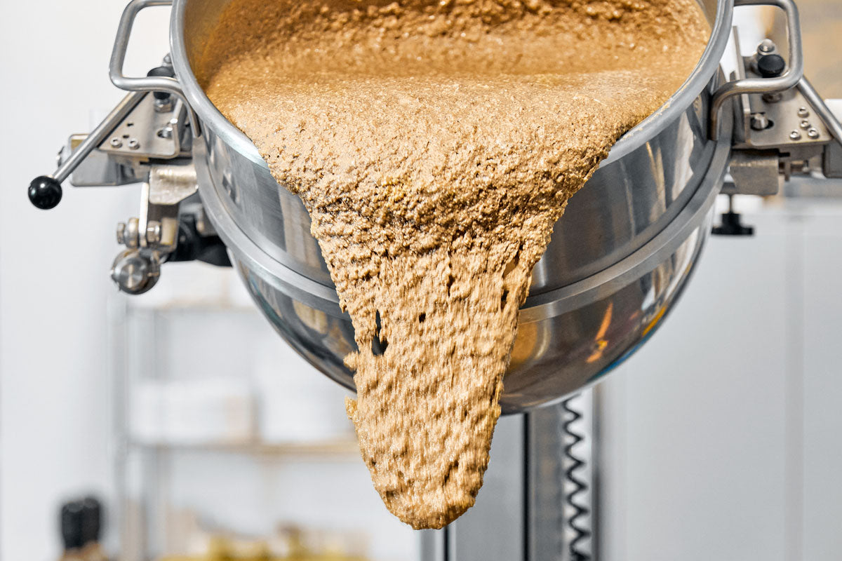 nut butter pouring from a large bowl in production facility