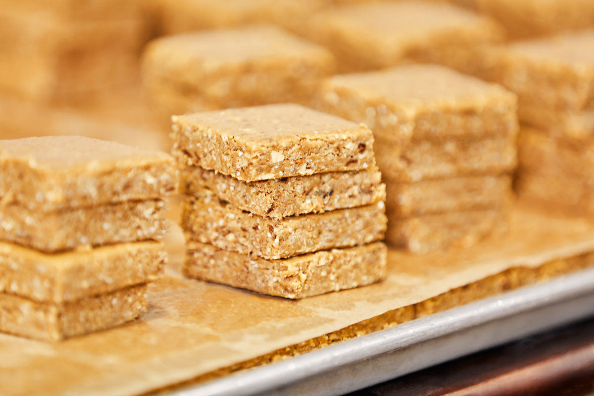 freshly made (and unwrapped) nut butter bars stacked on parchment-lined sheet trays